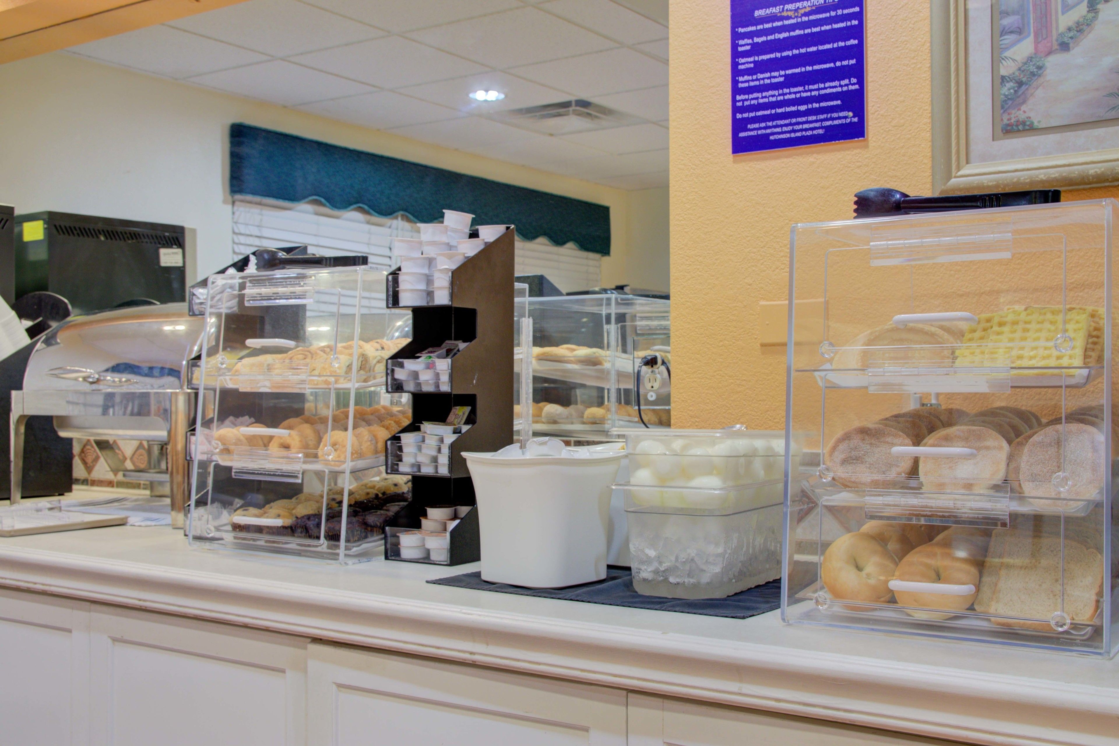 Un bufé de desayuno con diferentes alimentos en recipientes transparentes.