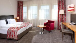 Una habitación de hotel con cama, escritorio, silla y lámpara.