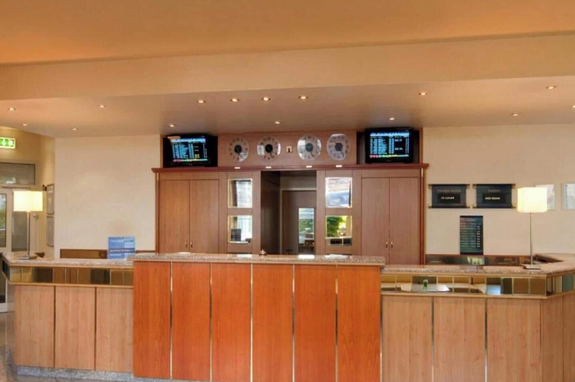 A reception area with wooden cabinets, a digital clock, and a television.