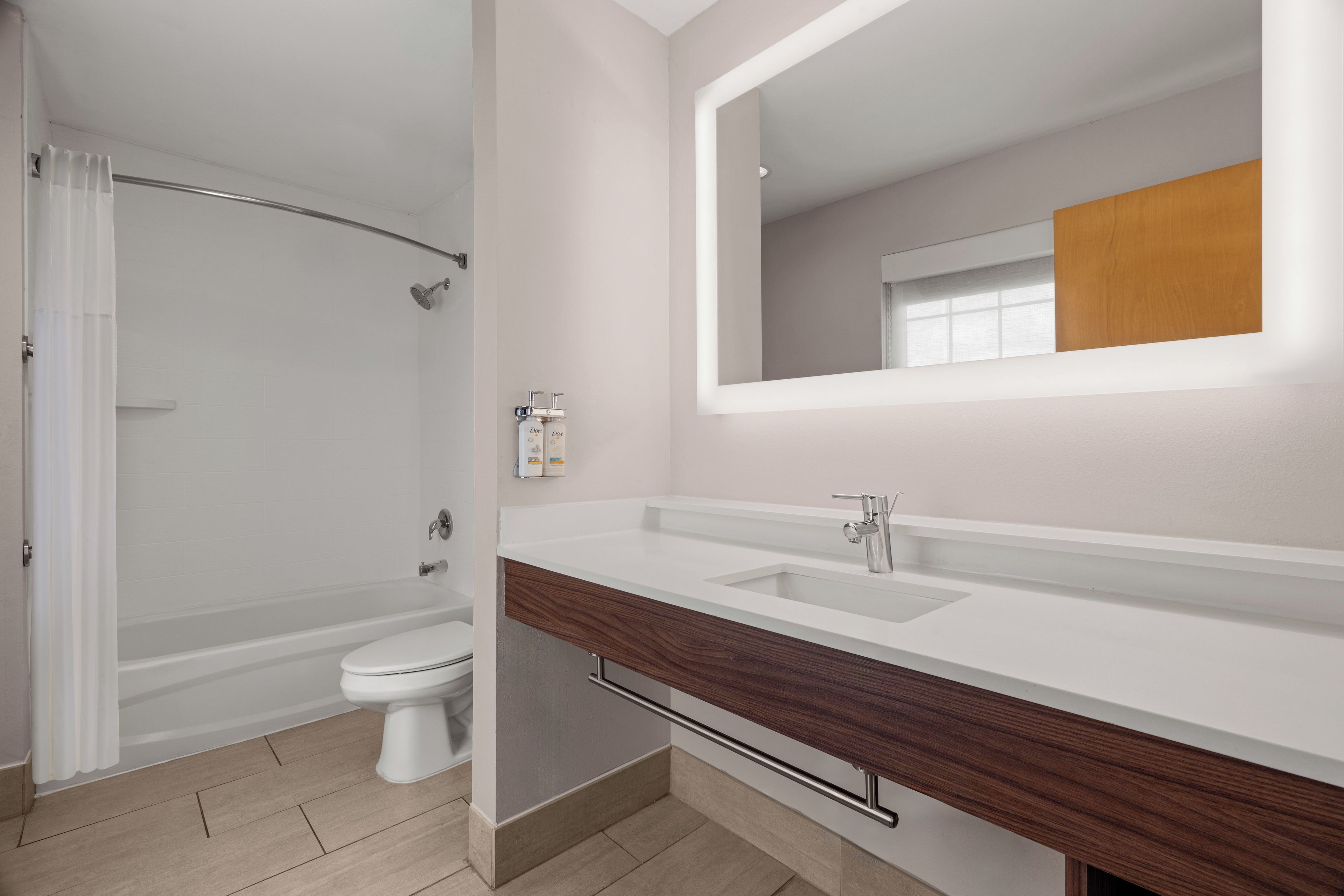 Un baño moderno con ducha, inodoro y tocador con espejo.