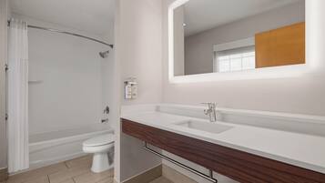 Un baño moderno con ducha, inodoro y tocador con espejo.