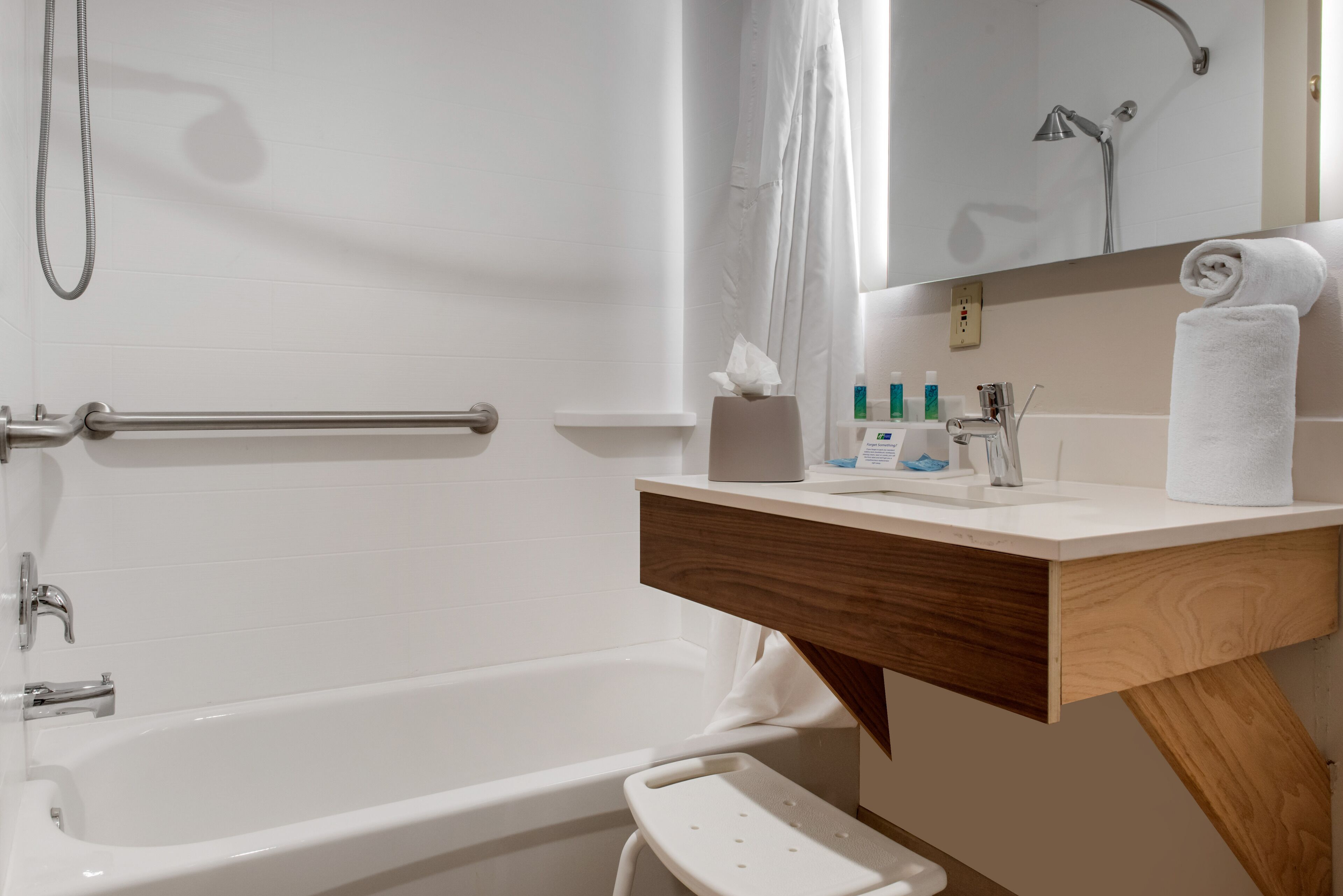 A modern bathroom with a bathtub, a shower, a vanity with a mirror, and a towel rack.