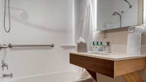 A modern bathroom with a bathtub, a shower, a vanity with a mirror, and a towel rack. - Holiday Inn Express & Suites Harrison by IHG (Harrison)