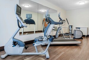 Uma academia equipada com aparelhos de ginástica, incluindo esteiras e um elíptico.