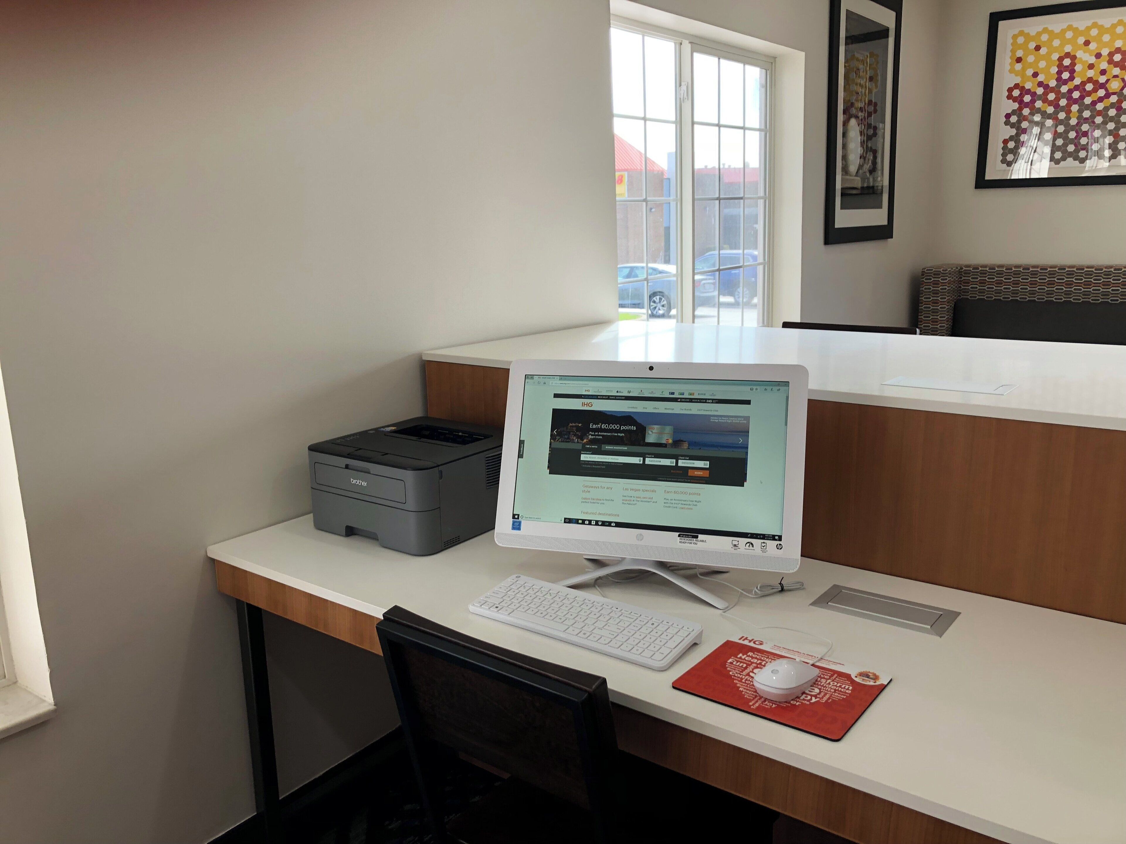 A desk with a desktop computer, a printer, and a keyboard.