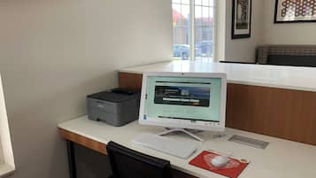 A desk with a desktop computer, a printer, and a keyboard.