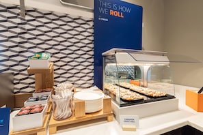 A breakfast buffet with a variety of food items, including rolls and pastries, and a sign indicating the availability of cinnamon sweet rolls. - Holiday Inn Express & Suites Harrison by IHG (Harrison)