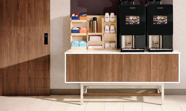 A modern kitchen with wooden cabinets, a coffee station with two espresso machines, and a variety of kitchen essentials on the counter.