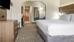 A hotel room with a large bed, a desk with drawers, a flat-screen TV, a chair, and a lamp. - Holiday Inn Express & Suites Harrison by IHG (Harrison)