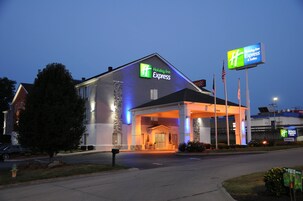 Edificio Holiday Inn Express con entrada despejada, fachada de piedra y señalización que indica la entrada.