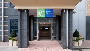 Holiday Inn Express -hotellin sisäänkäynti, jossa on lasiovi ja sen yläpuolella vihreä kyltti.