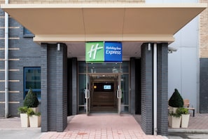 A Holiday Inn Express entrance with a glass door and a green sign above.