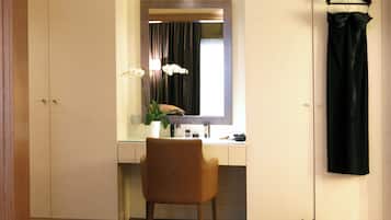 A room with a mirror, a chair, a hanging black dress, and a pair of shoes.