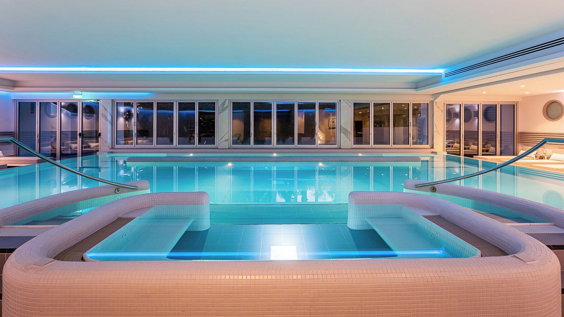 Een binnenzwembad, een buitenzwembad en parasols bij het zwembad