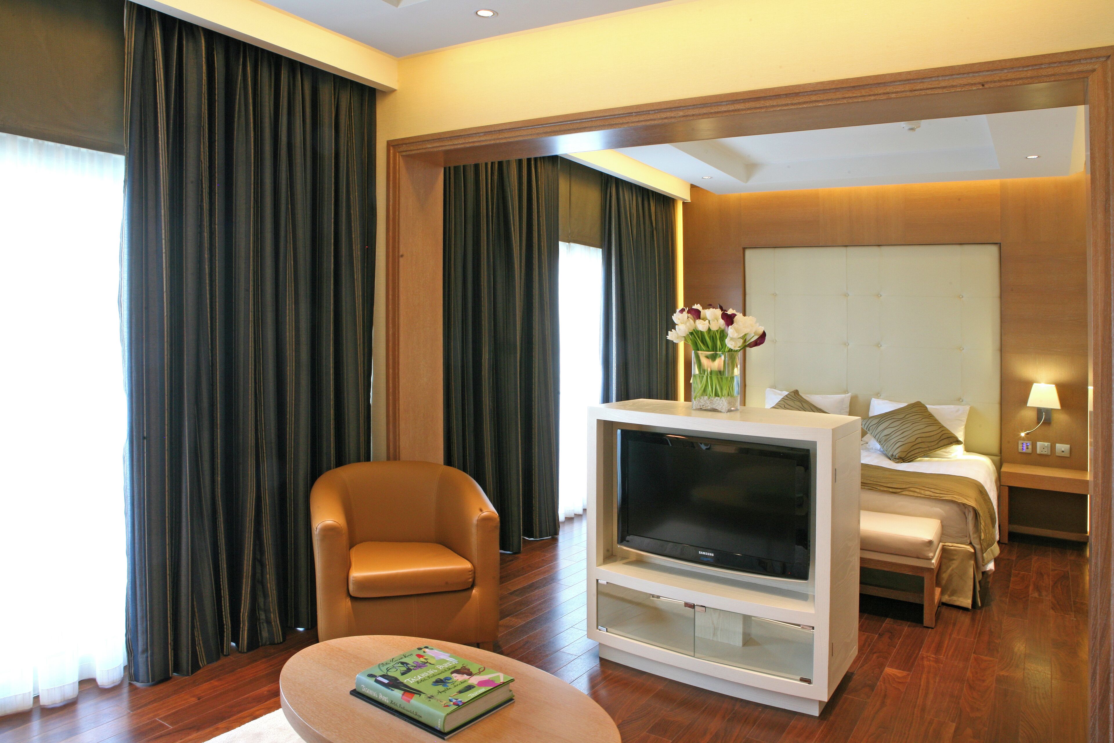A hotel room with a sofa, a TV, a bed, and a nightstand.