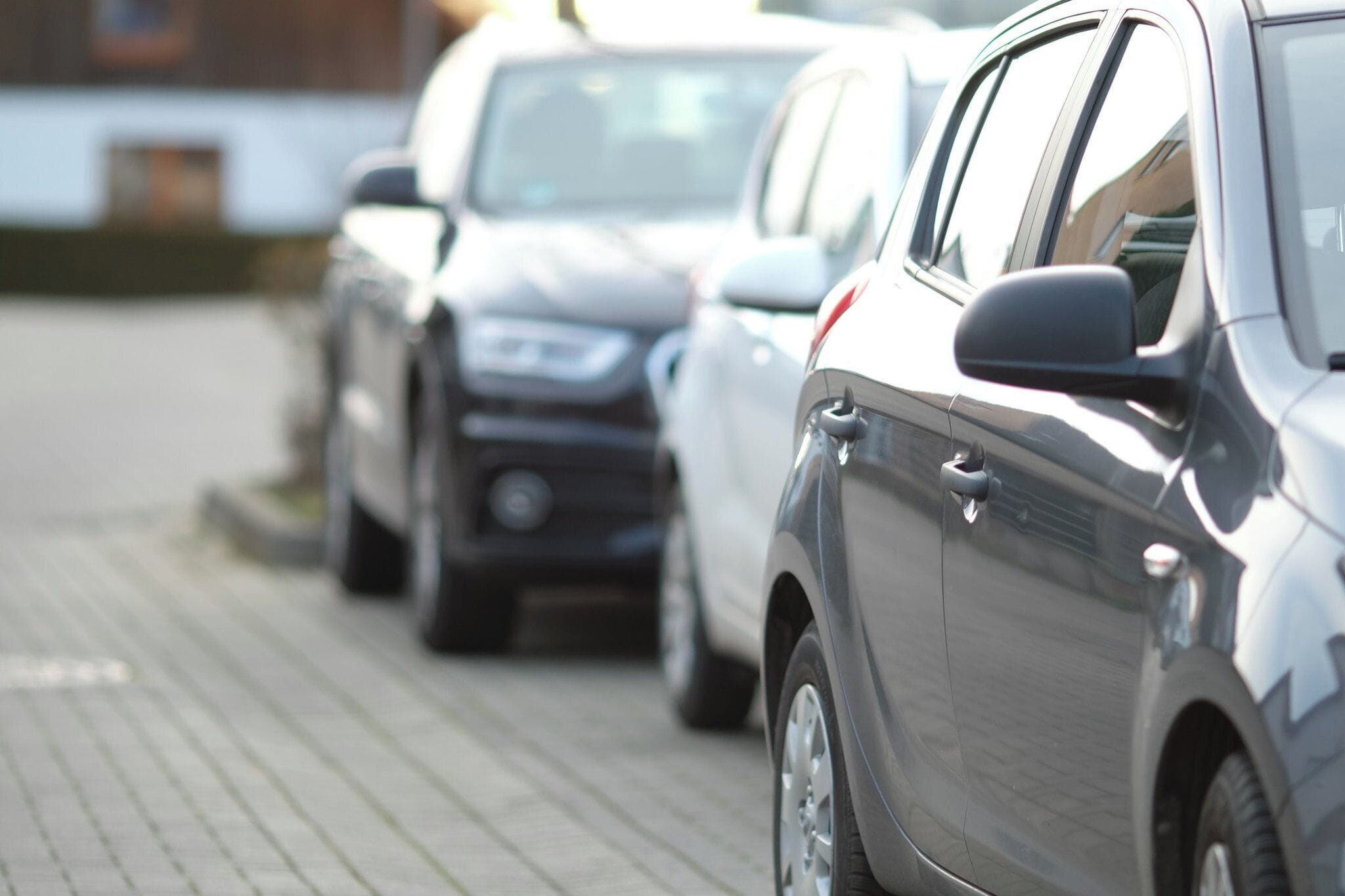 Una fila de coches aparcados sobre una superficie pavimentada.