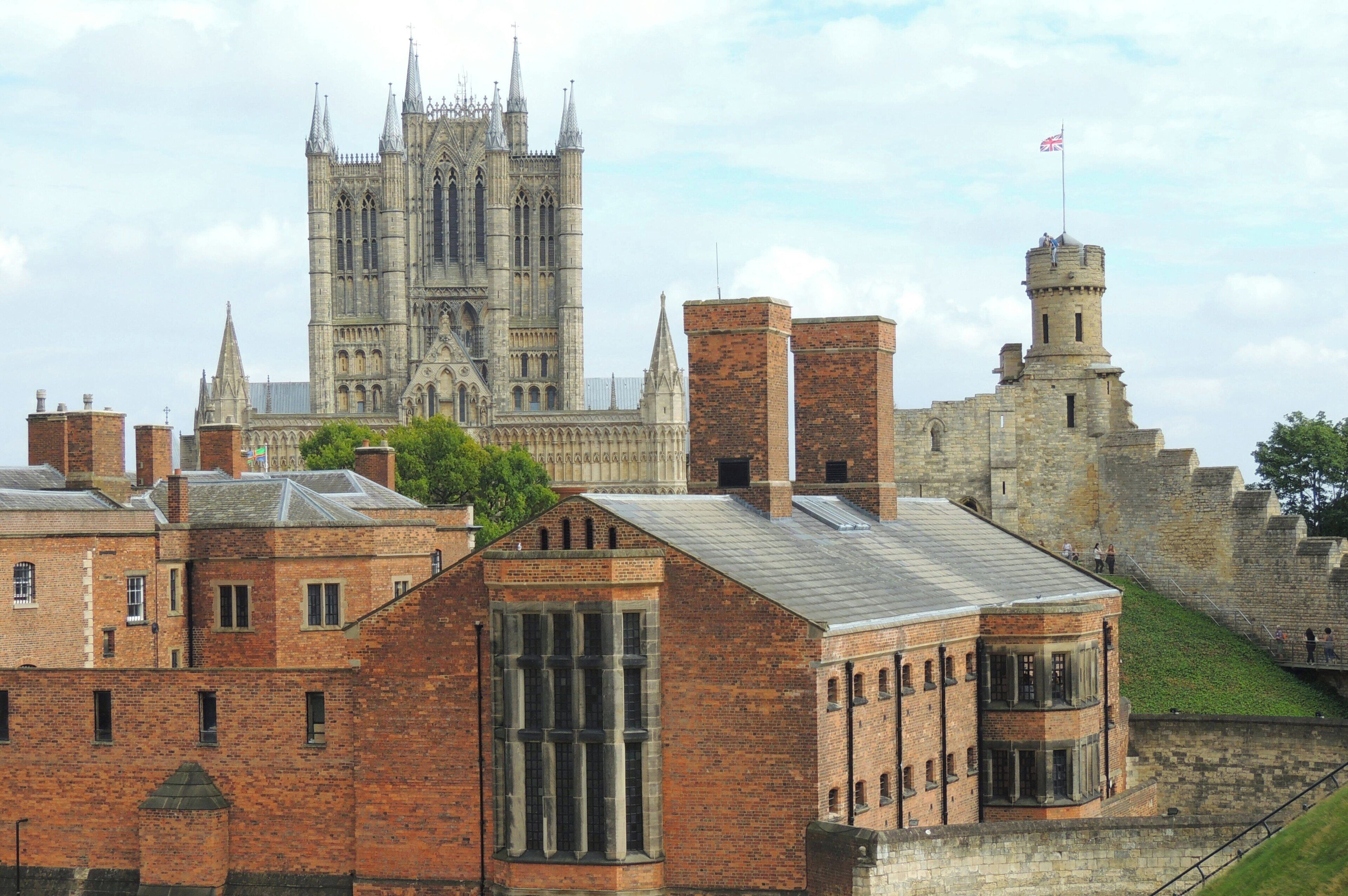 A historic building with a prominent tower and a large cathedral in the background.