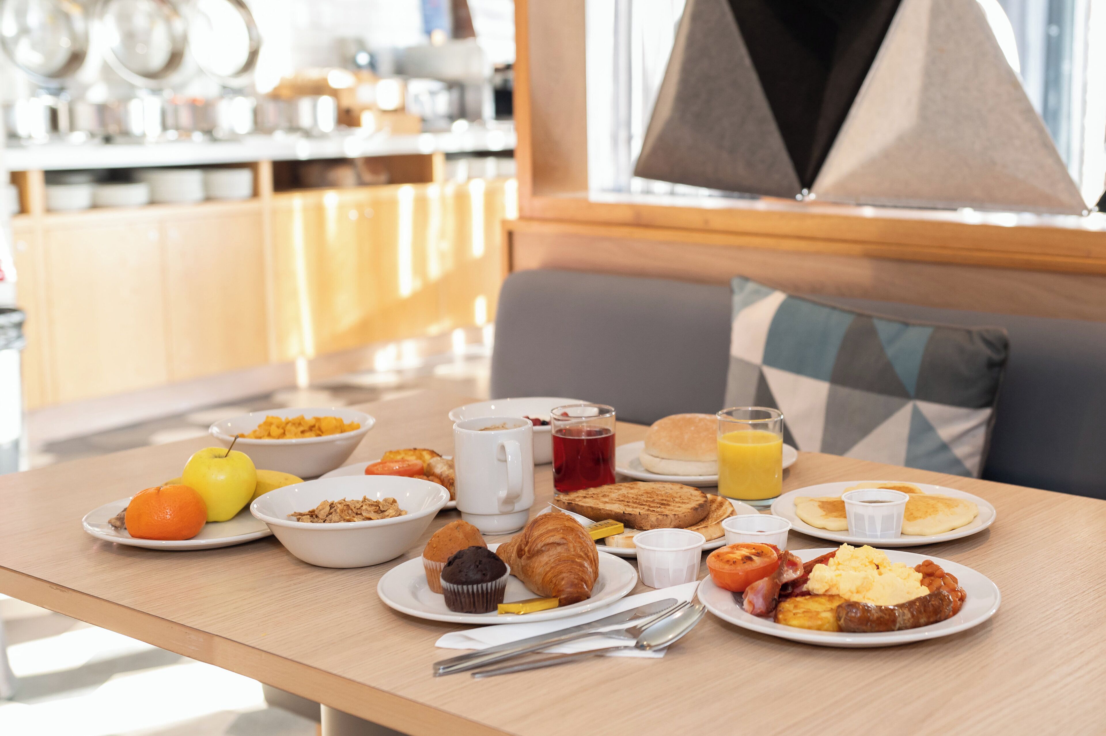 A breakfast table with various food items and utensils.