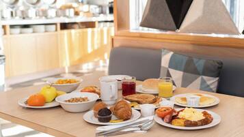 A breakfast table with various food items and utensils.