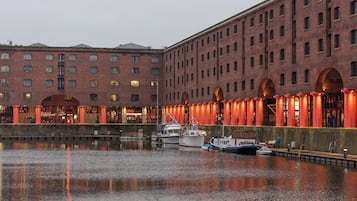 A waterfront building with multiple levels, large windows, and a reflection in the water.