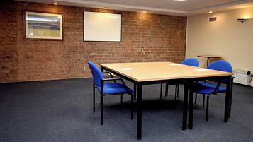A conference room with a brick wall, a wooden table, and blue chairs.