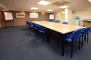 A conference room with a long table, blue chairs, white flip charts, and a water dispenser. - Holiday Inn Express Albert Dock by IHG (Liverpool)