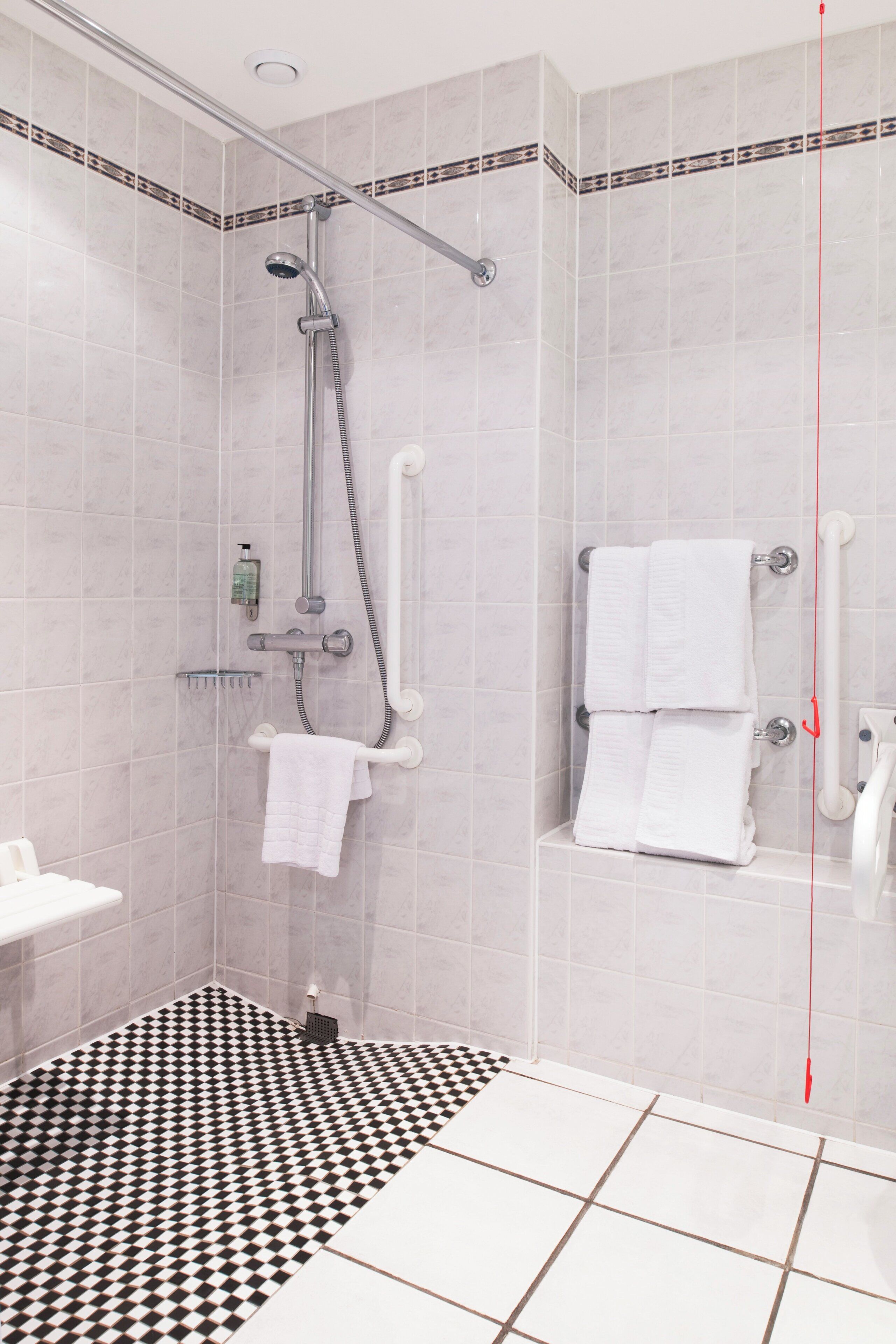 A modern bathroom with a shower, a white sink, and a checkered floor.