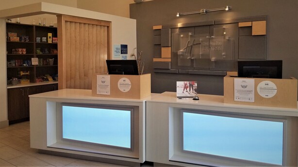 A reception desk with a digital display, a check-in counter, and a shelf with snacks.