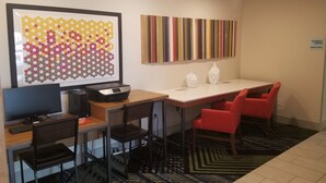A business center with a desk, chairs, a computer, and a printer.