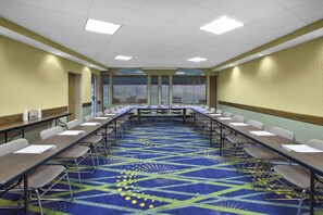 A conference room with a long table, chairs, and a patterned carpet.