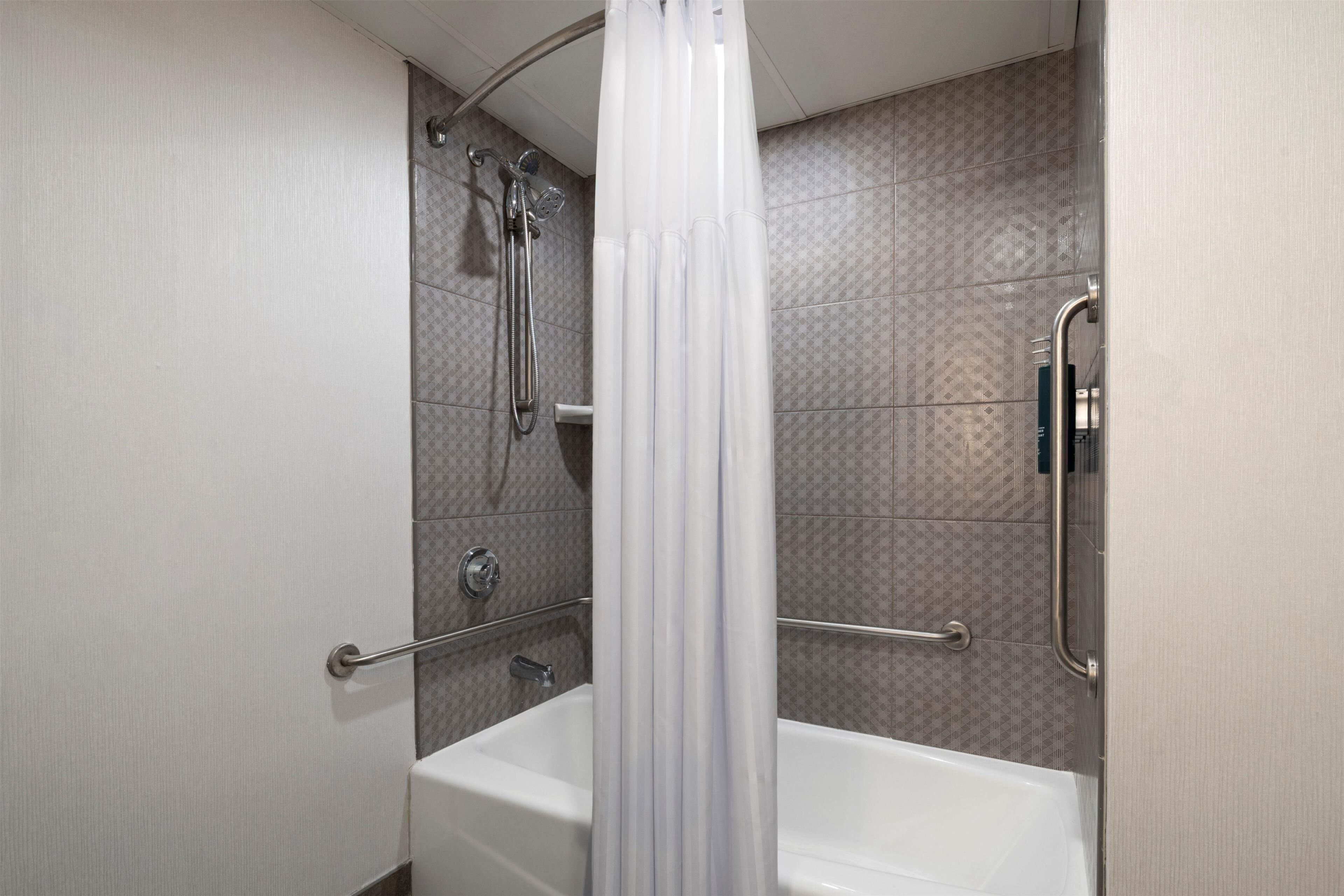 Un baño con bañera, ducha y barandilla.