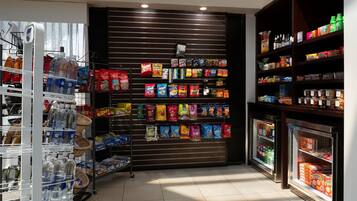 Un pasillo de supermercado con estantes llenos de aperitivos, bebidas y agua embotellada.