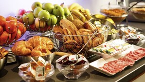 A buffet with various food items including fruits, pastries, and meats.