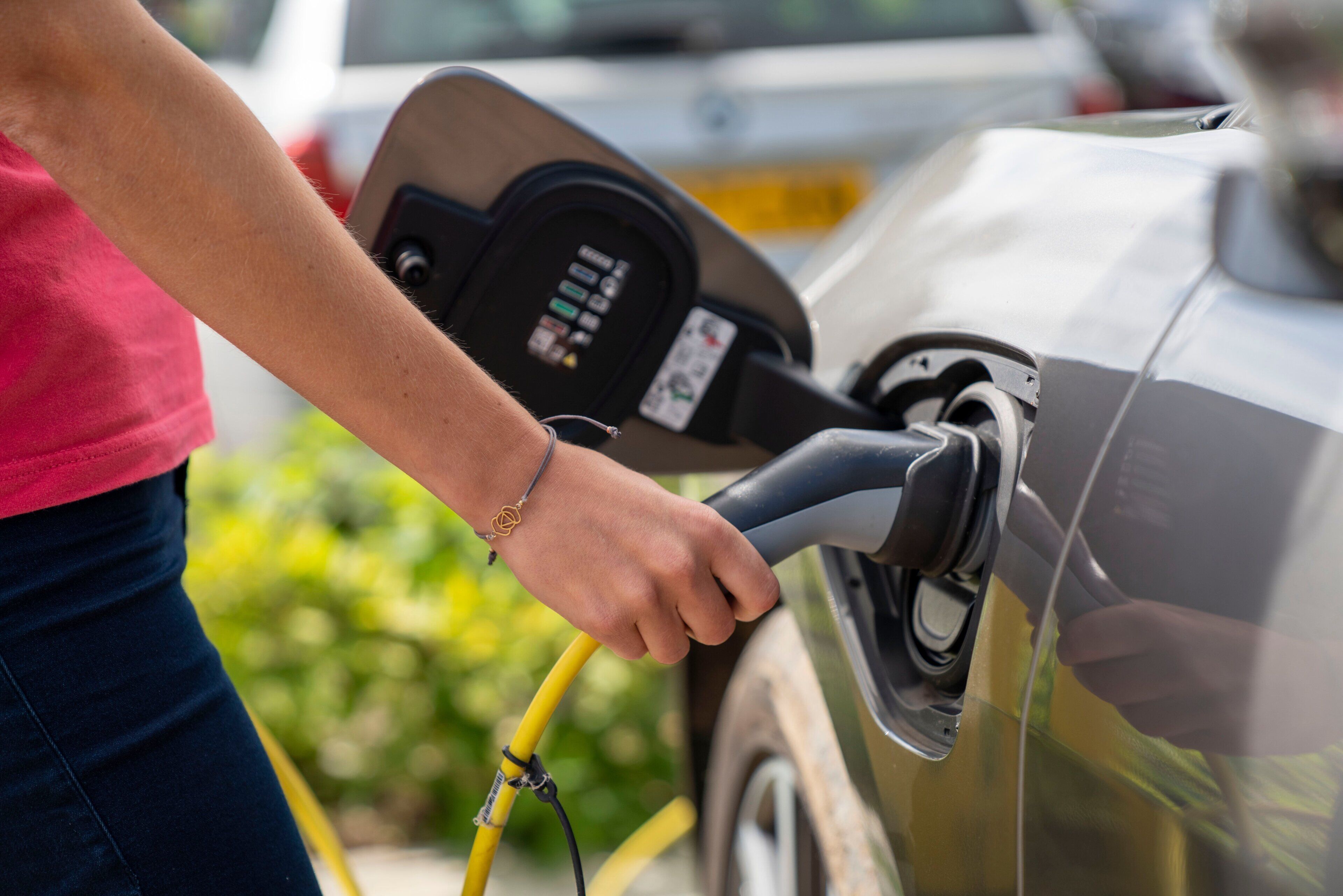 A person refueling a car with a yellow fuel nozzle.