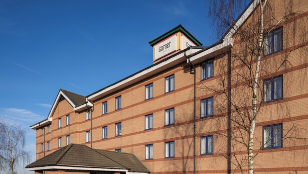 A multi-story hotel with a brick facade, multiple windows, and a covered entrance.