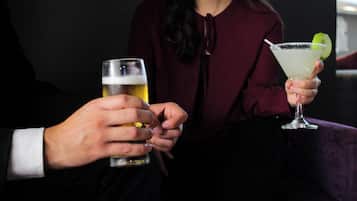 Dos personas sosteniendo un vaso de cerveza y un cóctel, respectivamente.