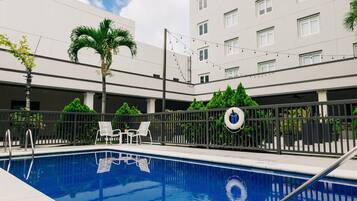 Una piscina al aire libre, sillones reclinables de piscina