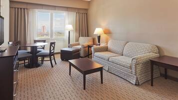 Habitación de hotel con una mesa de comedor, dos sillones, un sofá, una lámpara y un televisor.