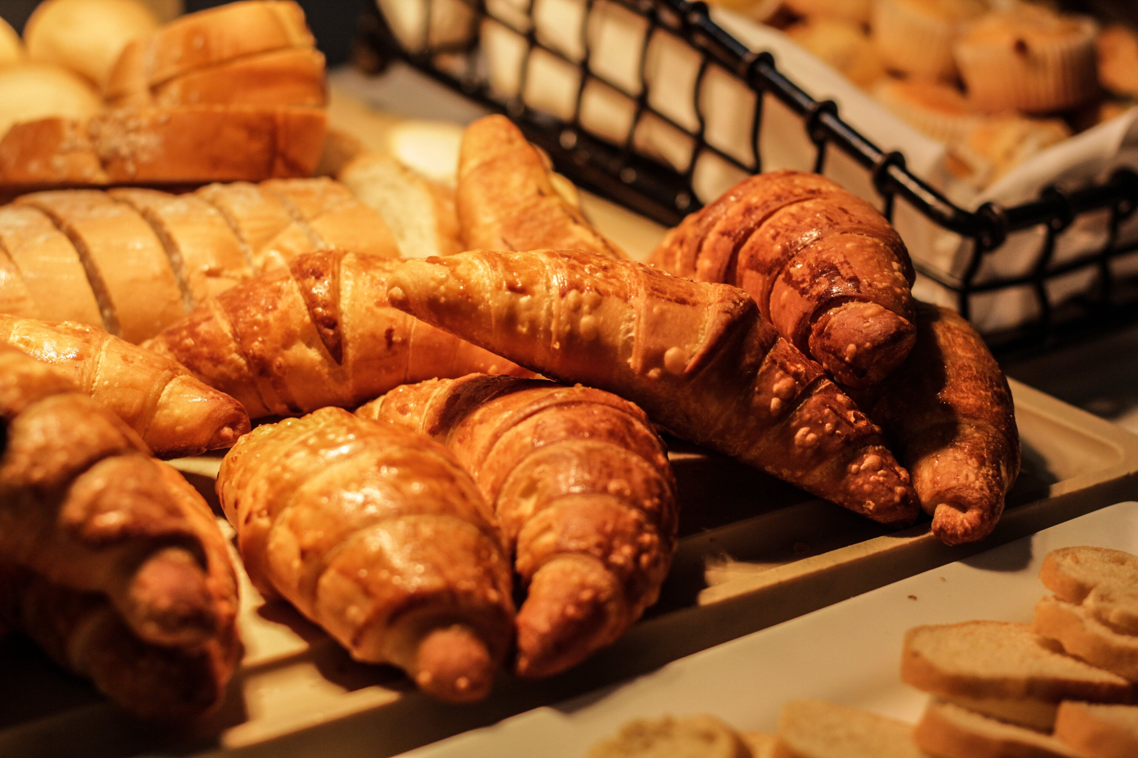 A display of various baked goods, including croissants and bread, arranged on a tray.
