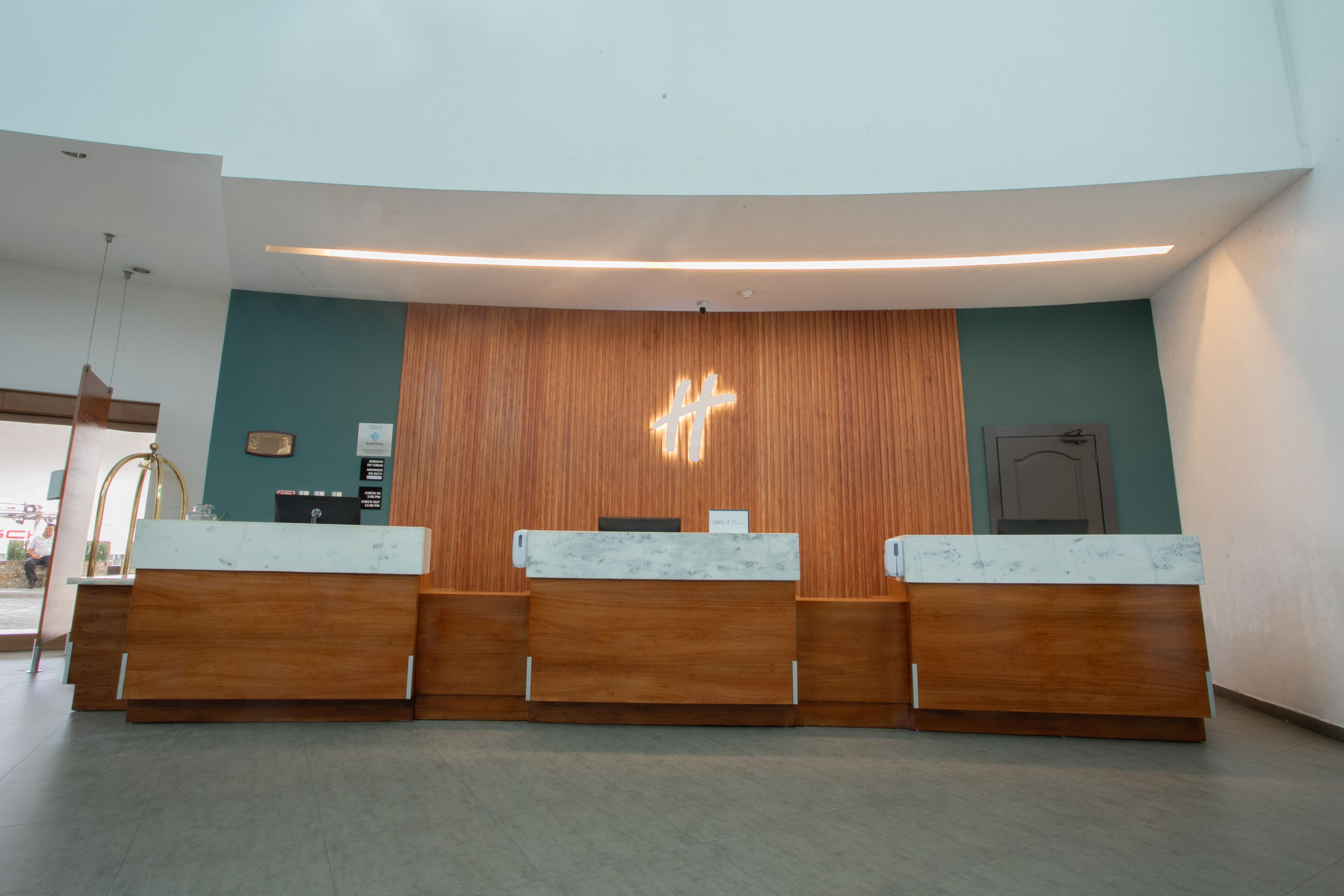 Un espace d’accueil doté d’un comptoir de réception en bois et d’un luminaire moderne.