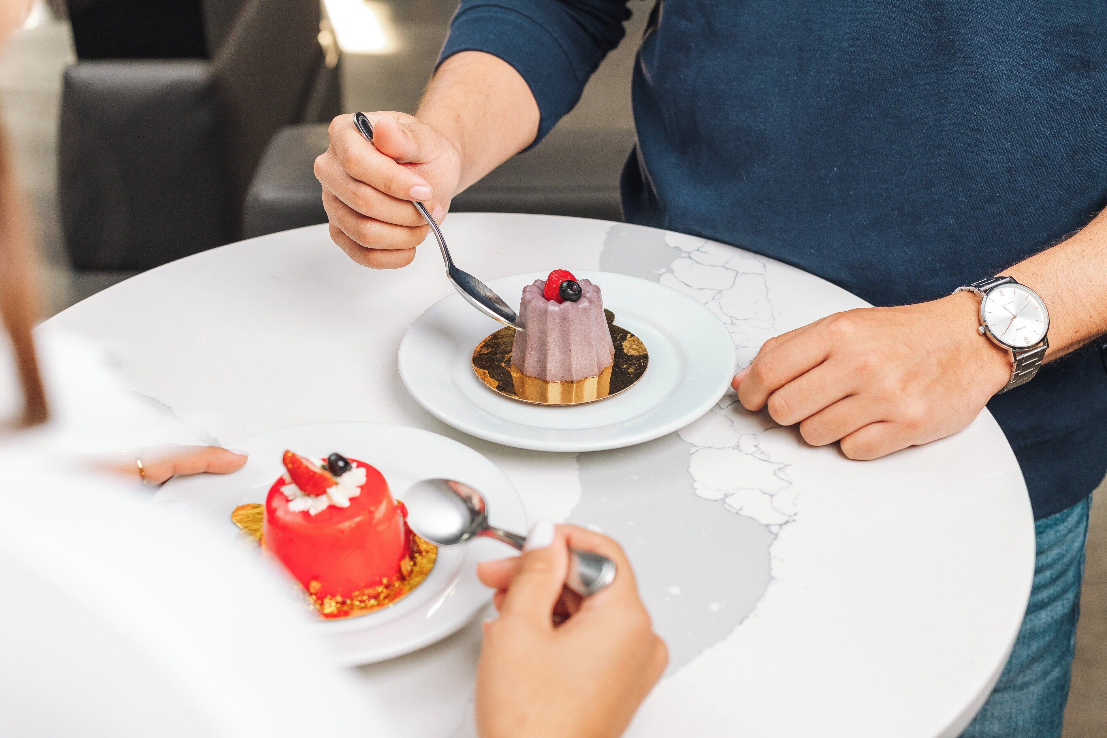 Eine Person serviert ein Dessert auf einem weißen Marmortisch.