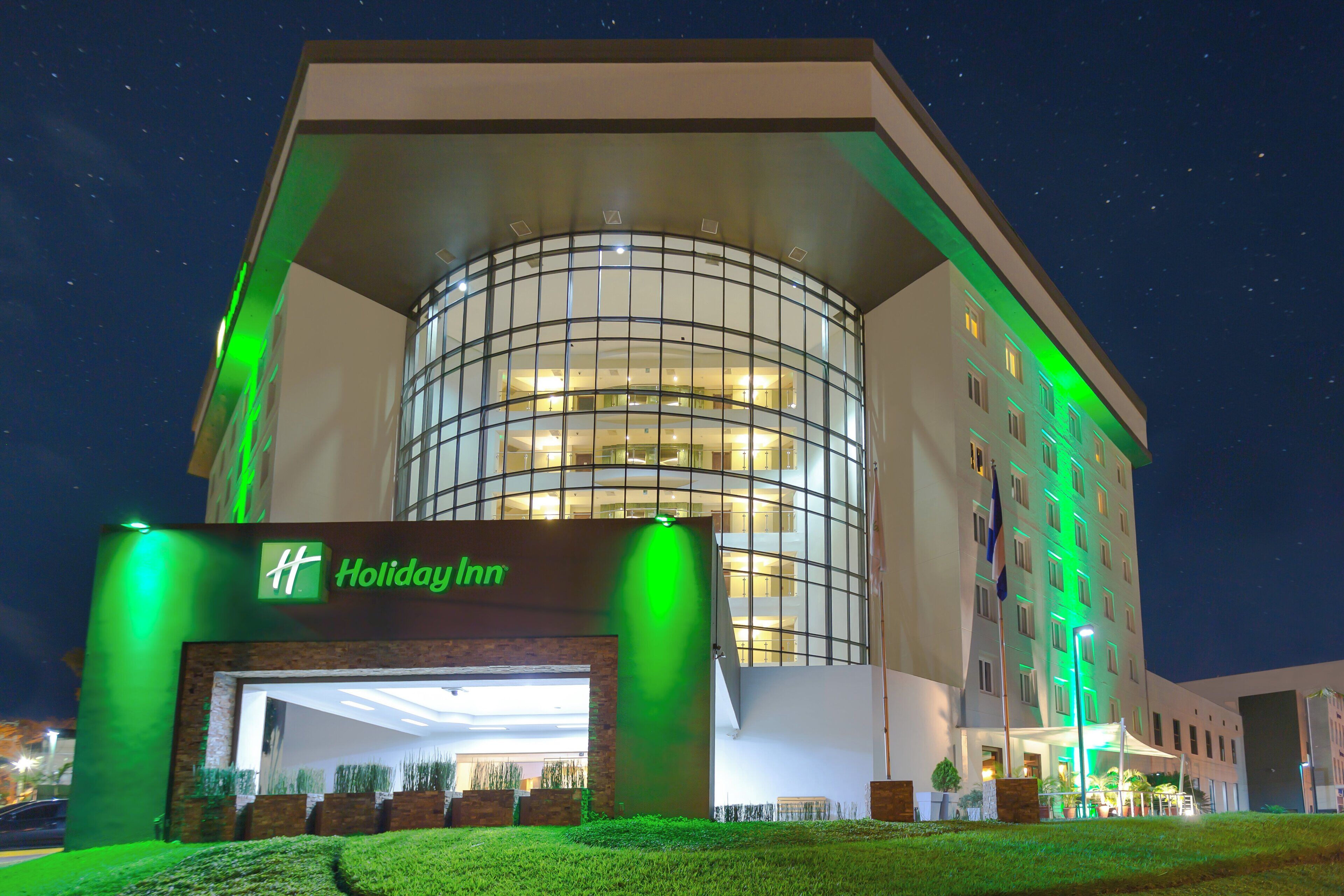 A Holiday Inn hotel with a modern design, featuring a prominent glass facade and a well-lit entrance.