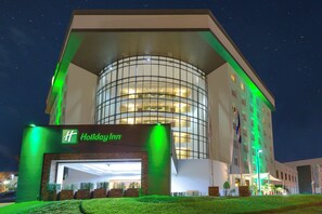Ein Holiday Inn Hotel mit modernem Design, das eine auffällige Glasfassade und einen gut beleuchteten Eingang zeigt.