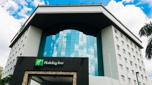 Un hôtel Holiday Inn au design moderne, caractérisé par une façade en verre remarquable et une entrée encadrée de pierres.