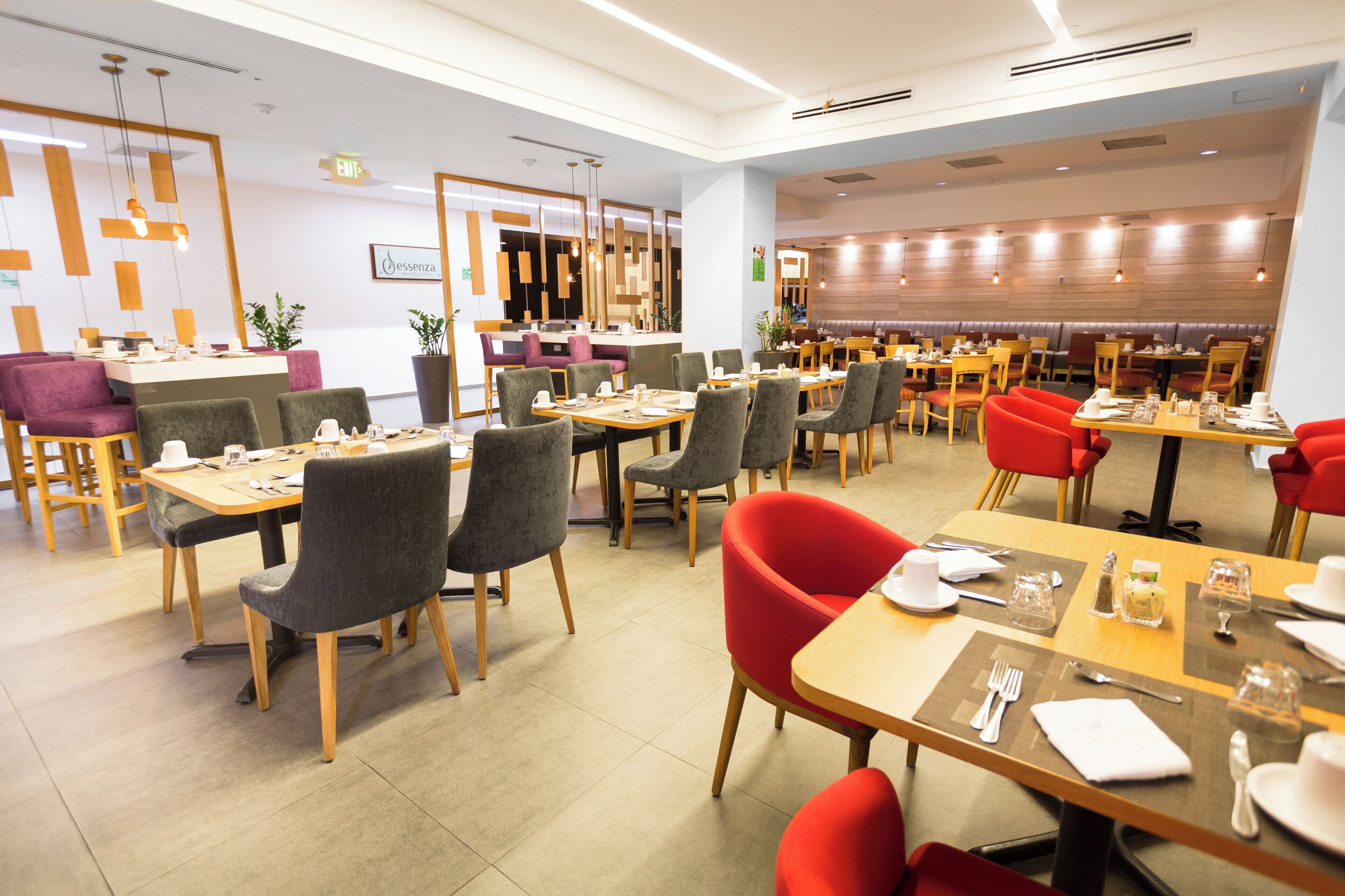 En moderne restaurant med flere spiseområder, herunder både siddebåse og borde, samt et barområde.