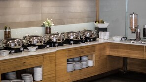 Enjoy a diverse selection of dishes at our buffet, featuring a range of covered food stations and neatly arranged plates.