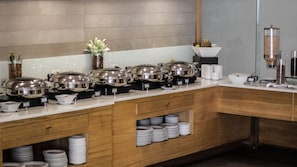 Enjoy a diverse selection of dishes at our buffet, featuring a range of covered food stations and neatly arranged plates.