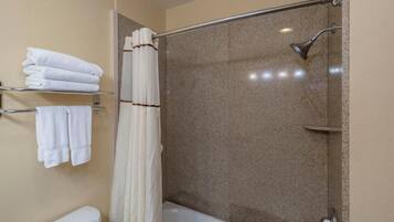 Un bagno con doccia, toilette e asciugamani piegati su un portascopevoli.