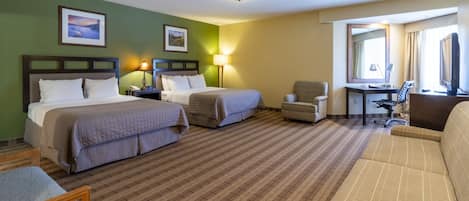 A hotel room with two beds, a desk, a chair, and a sofa.