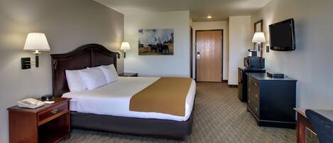 Habitación de hotel con una cama grande, lámparas de noche, televisión, escritorio y una puerta que da a otra habitación.